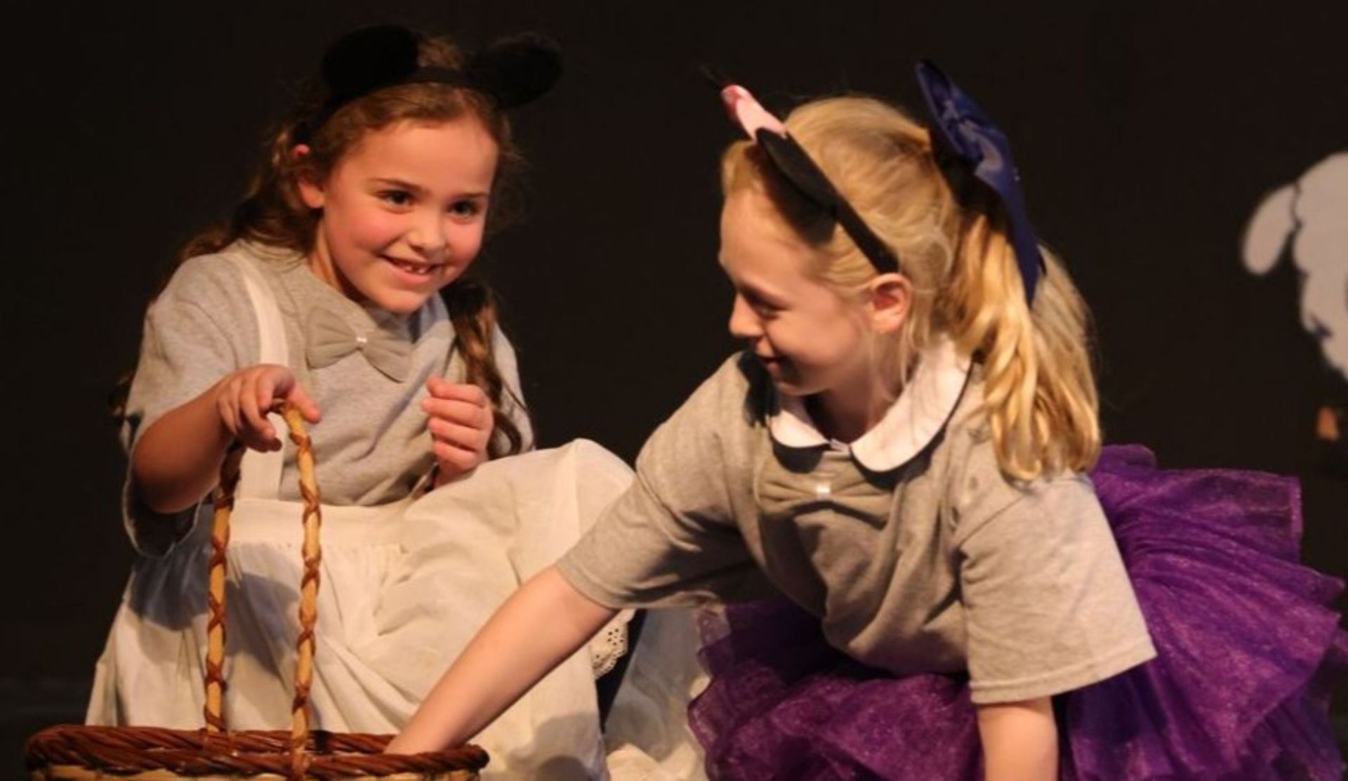 Two young students in costume performing together on stage during a school production.