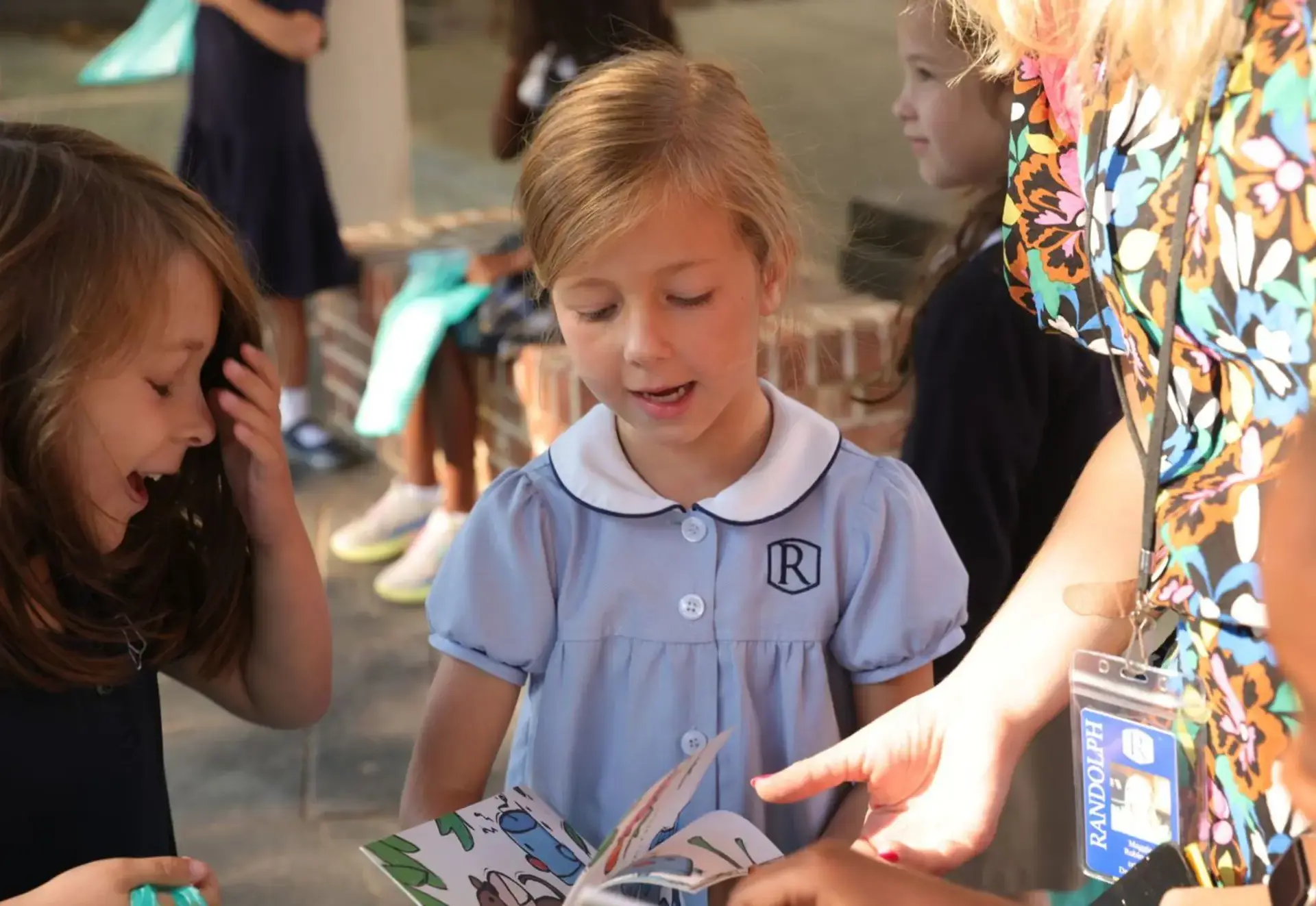 Teacher reading with young students during an outdoor learning activity.