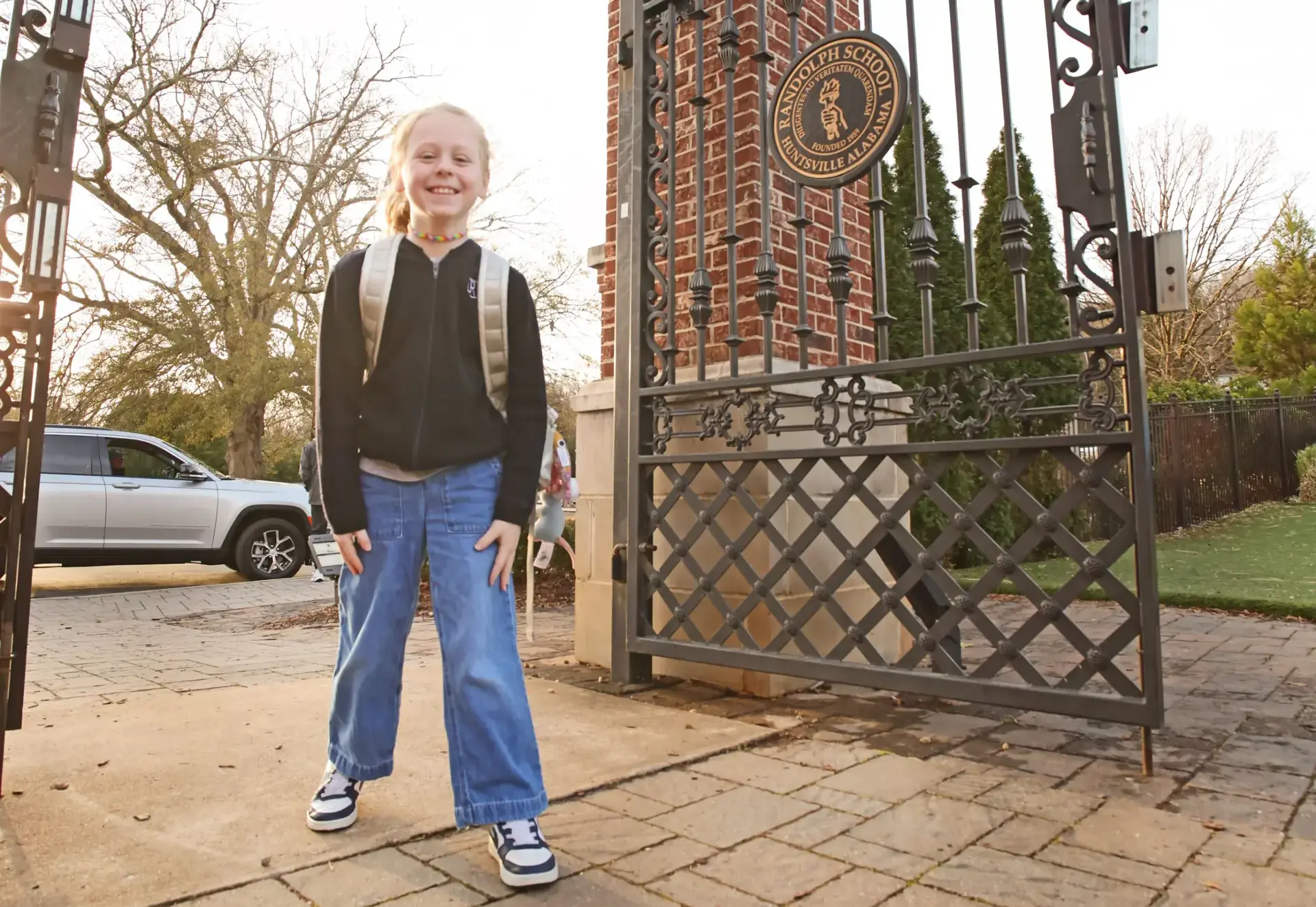tudent with a backpack standing at the Randolph School entrance gate.
