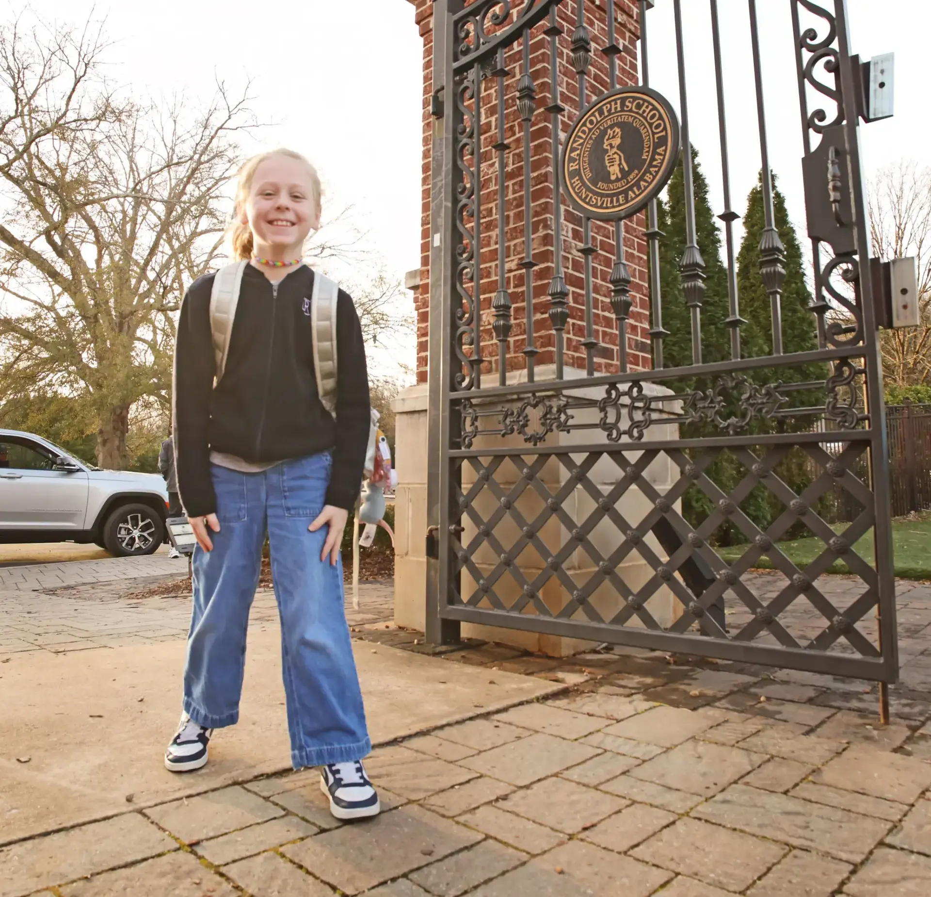 Student with a backpack standing at the Randolph School entrance gate.
