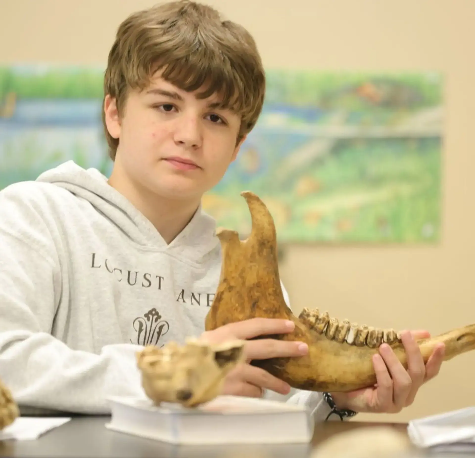 Student examining a large animal jawbone specimen during a hands-on science lesson.