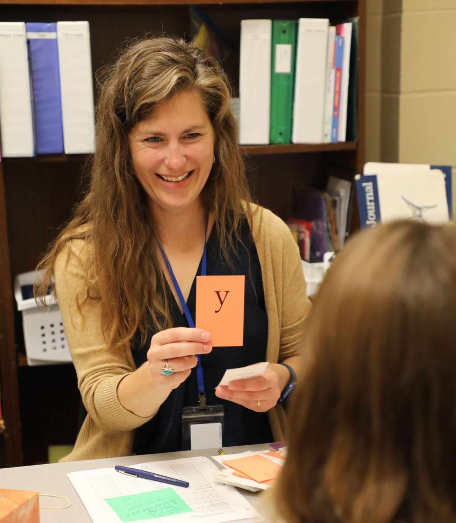Teacher holding a letter card during a one-on-one reading lesson with a student.