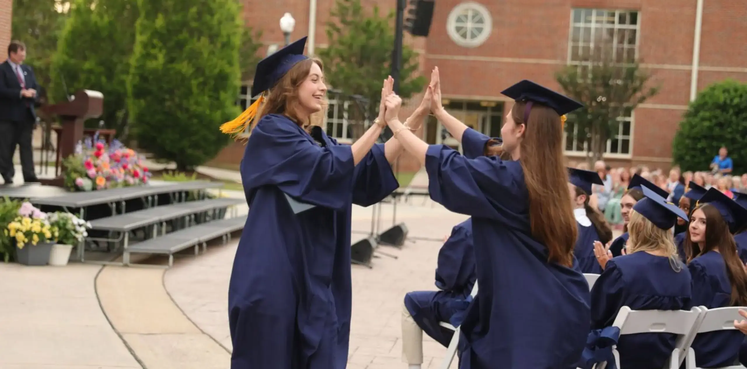 Graduating students celebrating with a high-five during commencement.