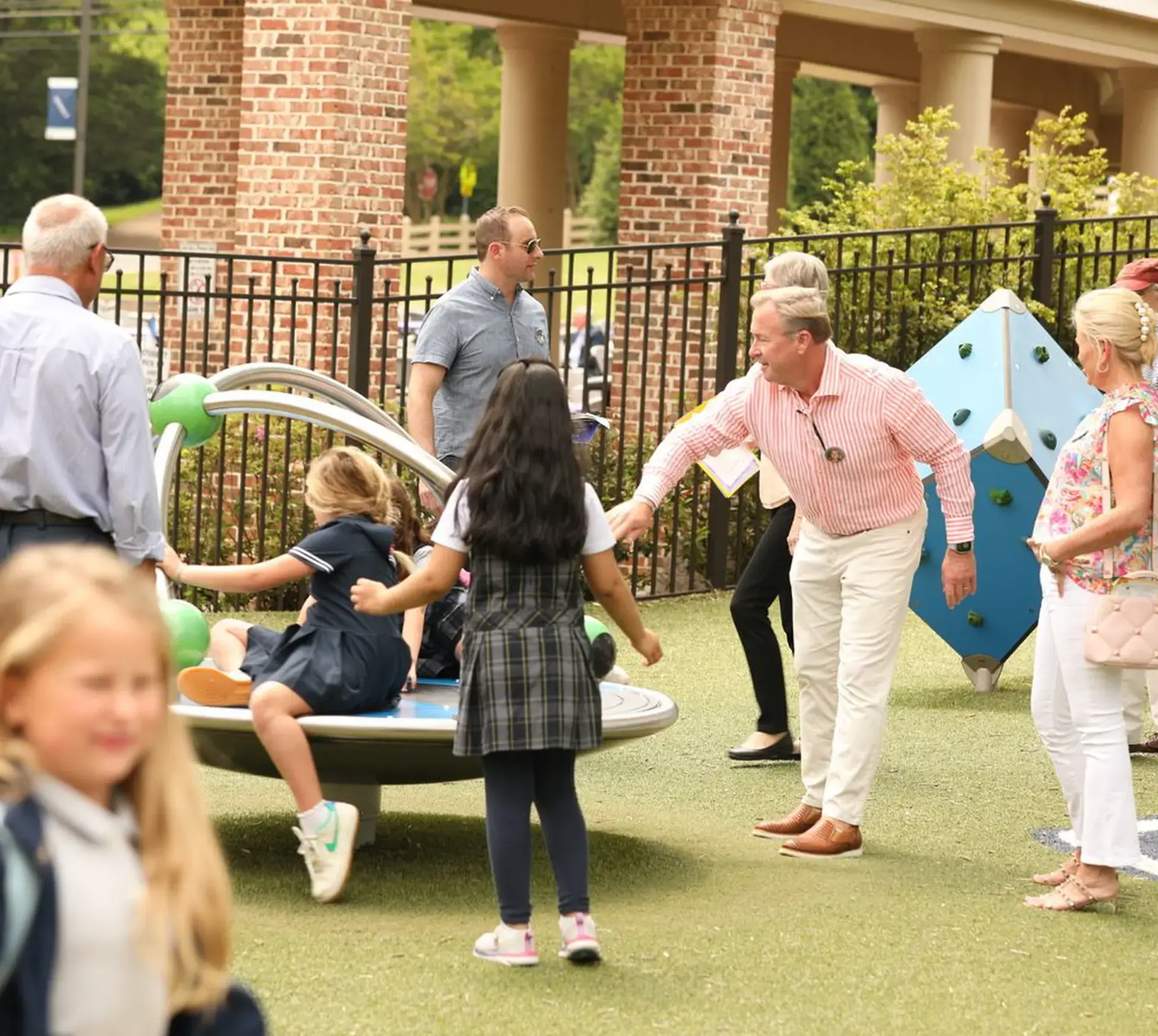 Parents and grandparents push students on a merry-go-round on the playground at Randolph. 