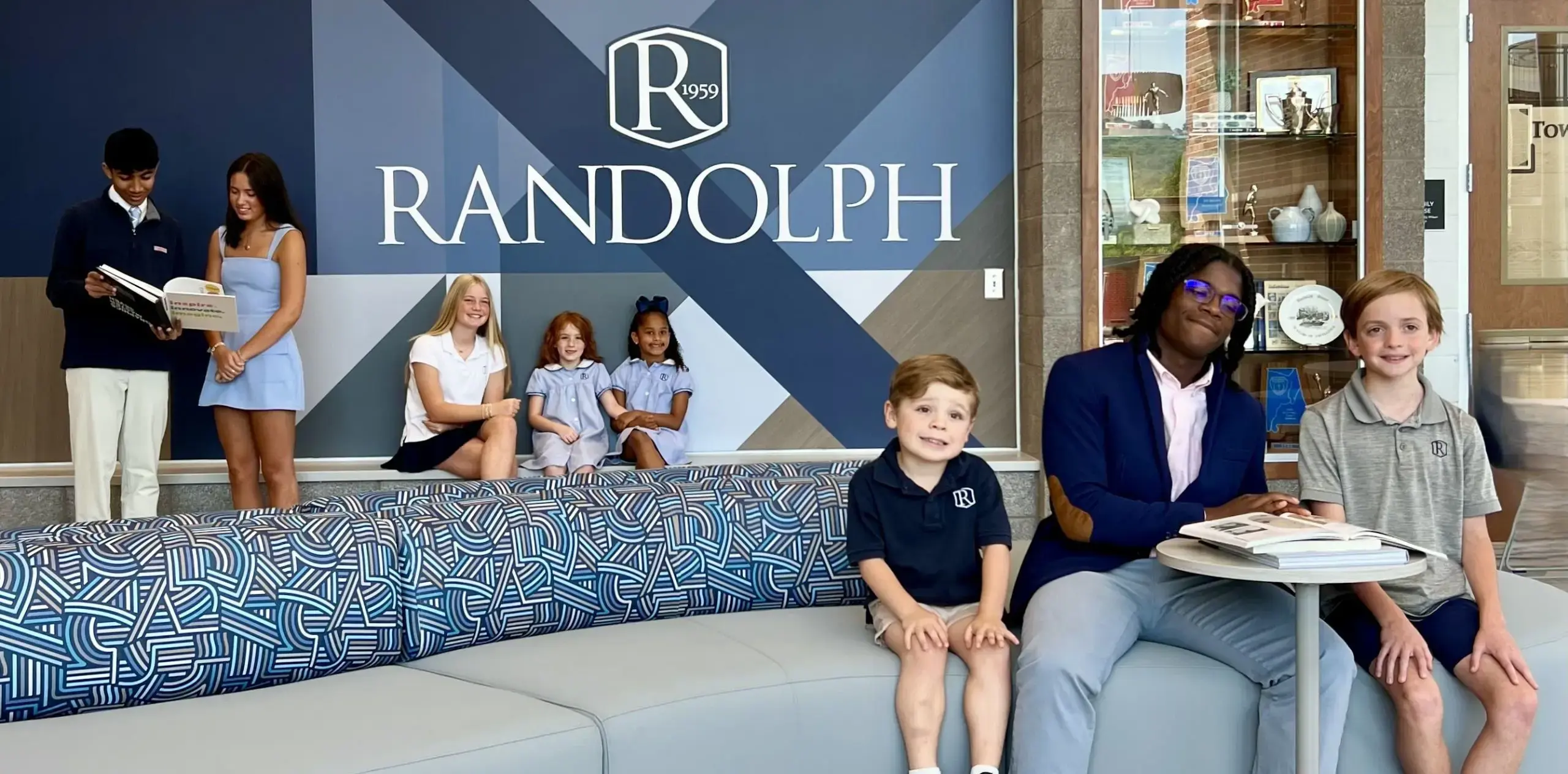 Students smiling in front of the Randolph School banner