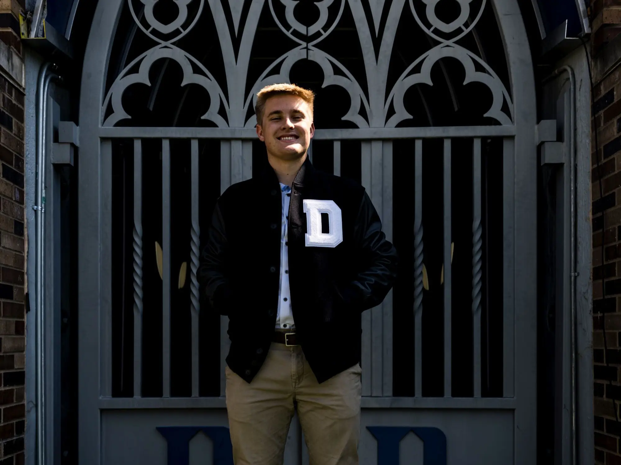 Student standing in front of an ornate campus gate.