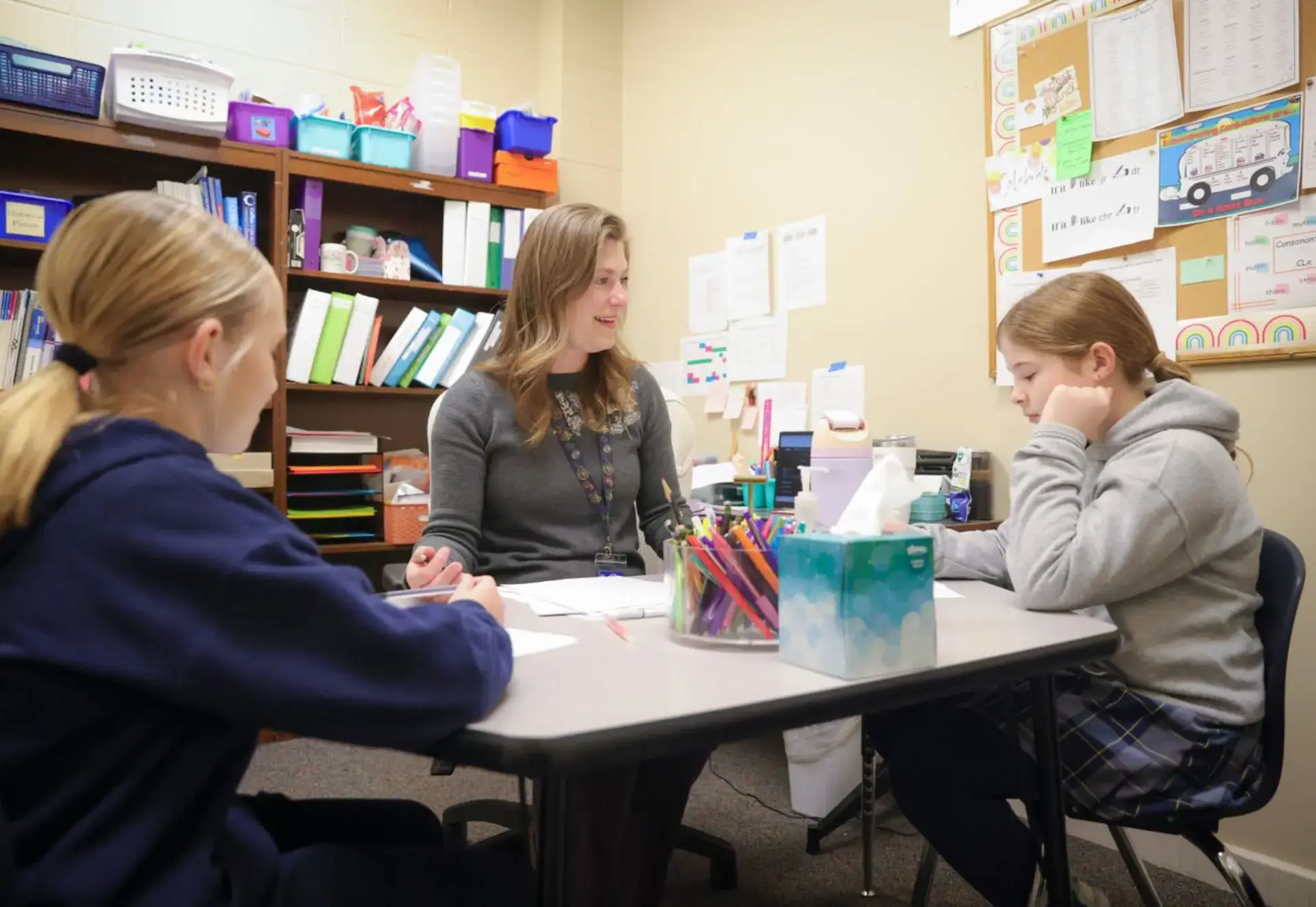Teacher working with two students during a small-group learning session.