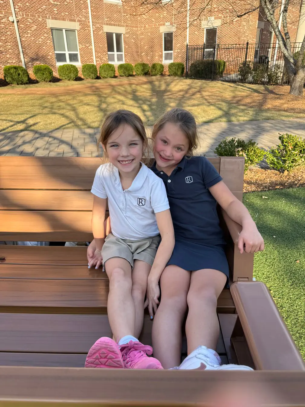 Two girls sitting on a bench, smiling together, representing a supportive community.