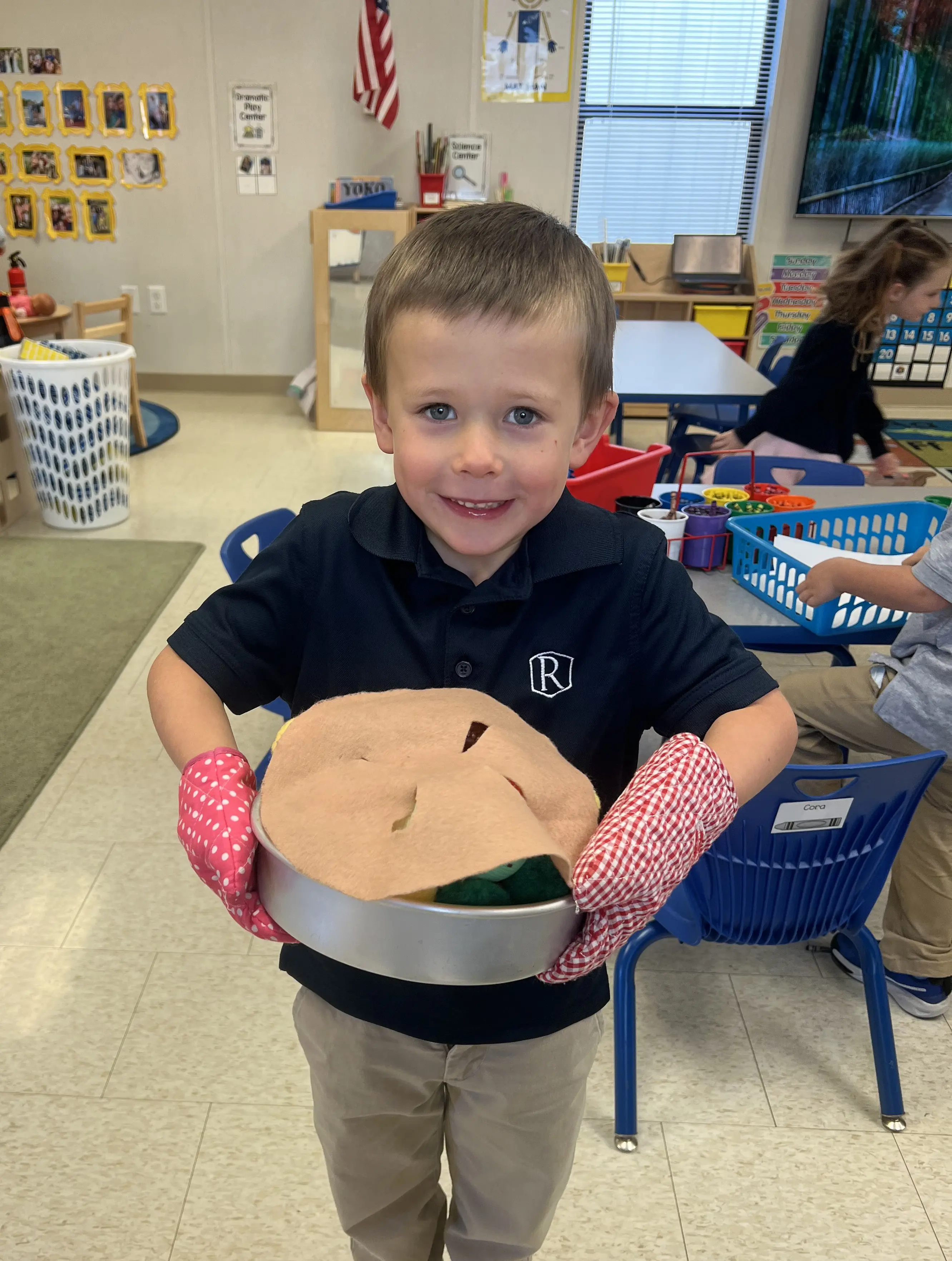 A  young boy, a Randolph student, smiling in his classroom during interactive play.