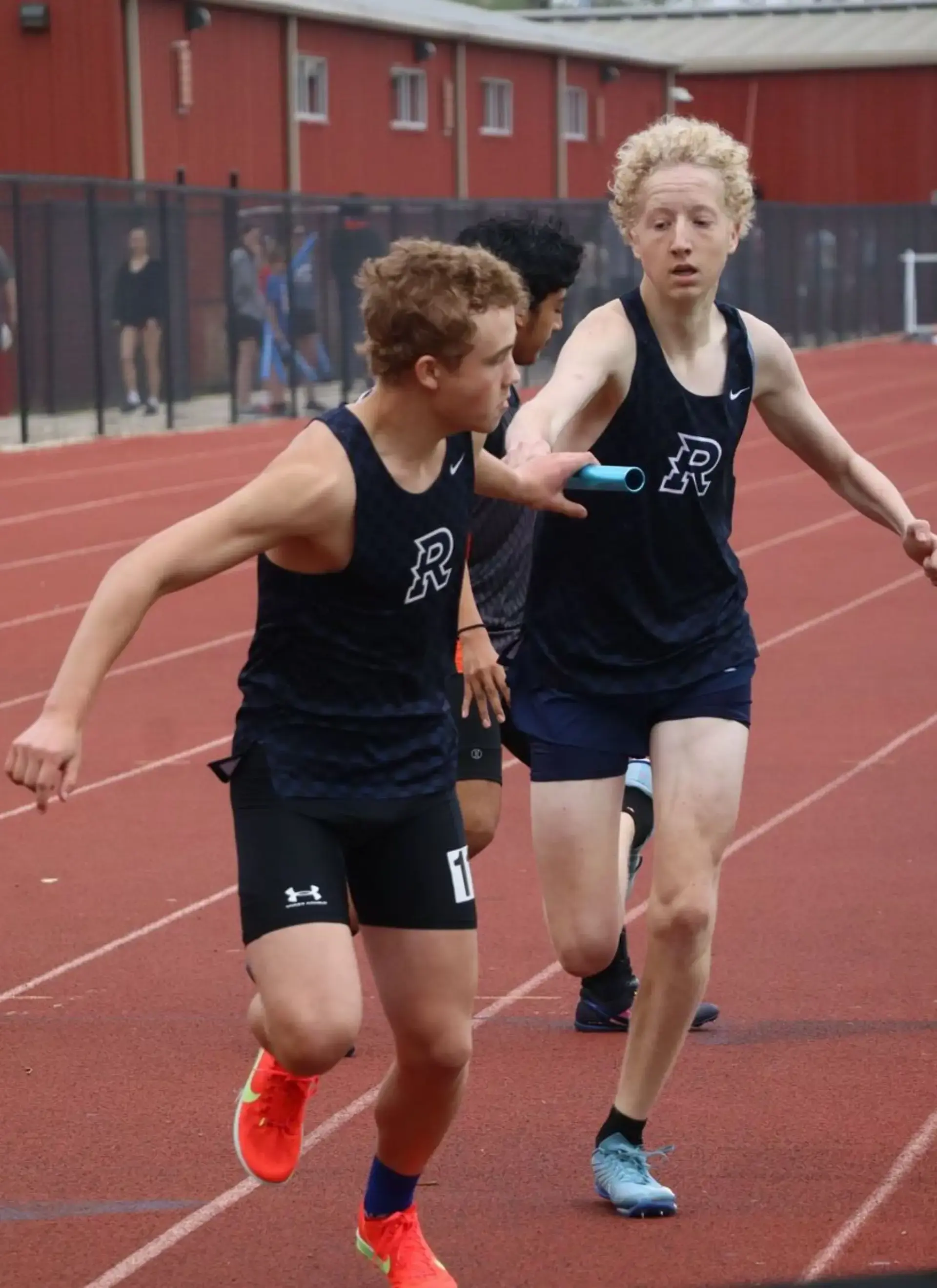 Students exchanging a baton during a relay race.