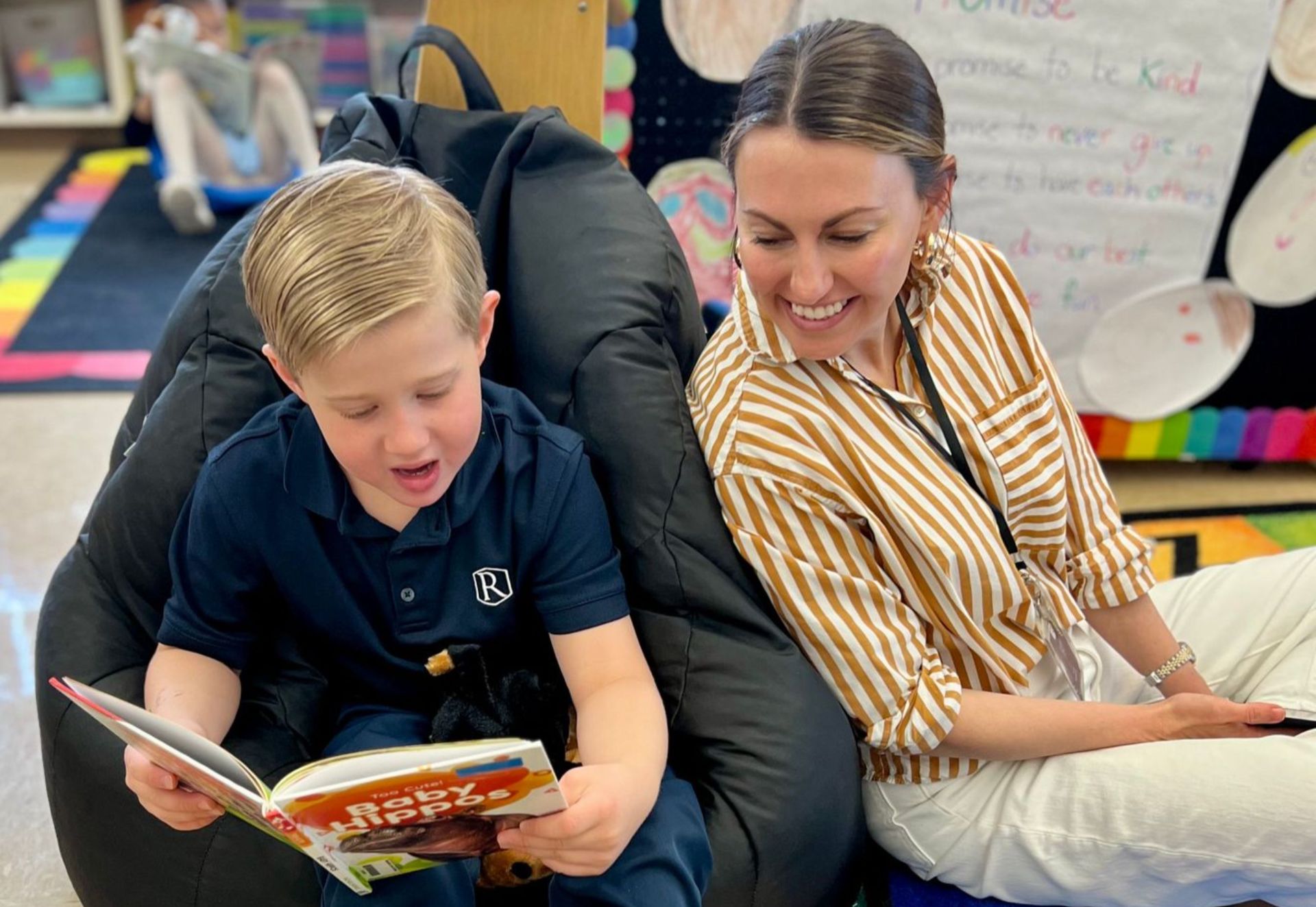 Student reading a book with a teacher
