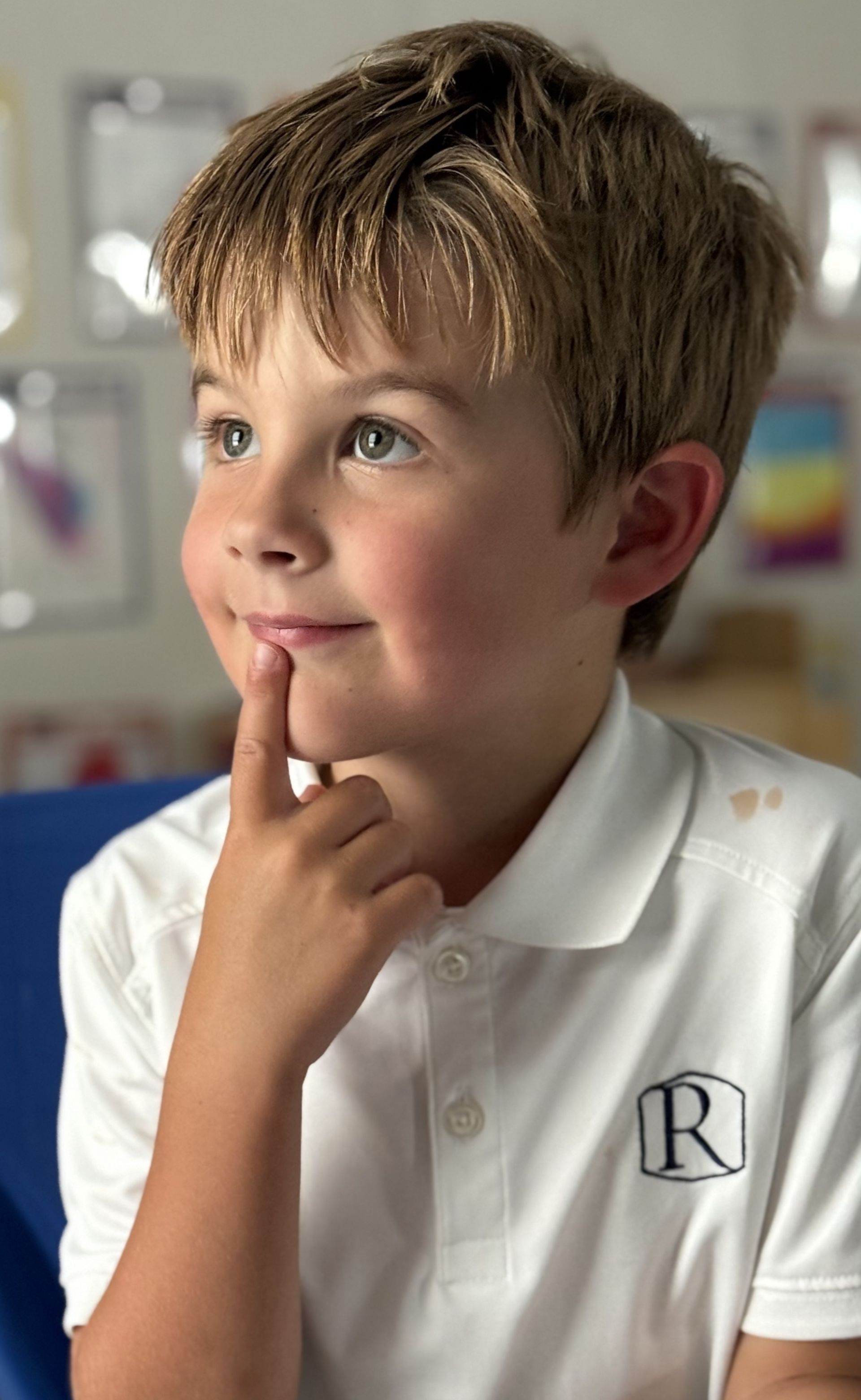 Young student in a Randolph polo shirt thoughtfully listening in the classroom.