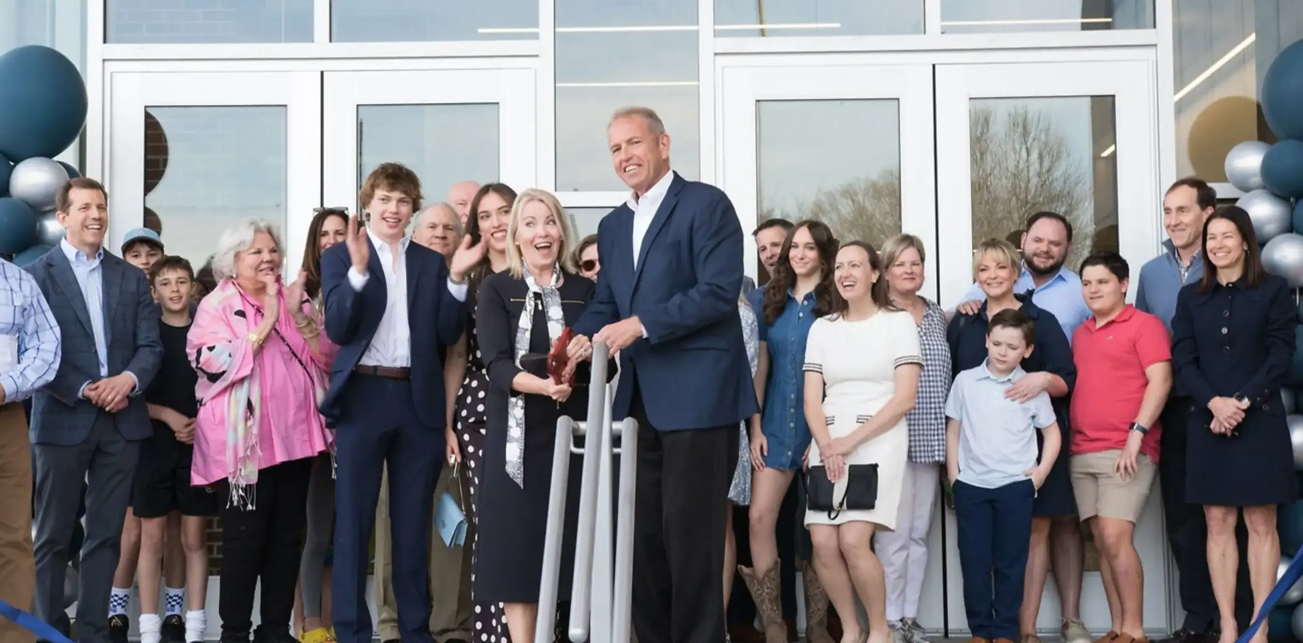 Group gathered outside a building during a ribbon-cutting celebration
