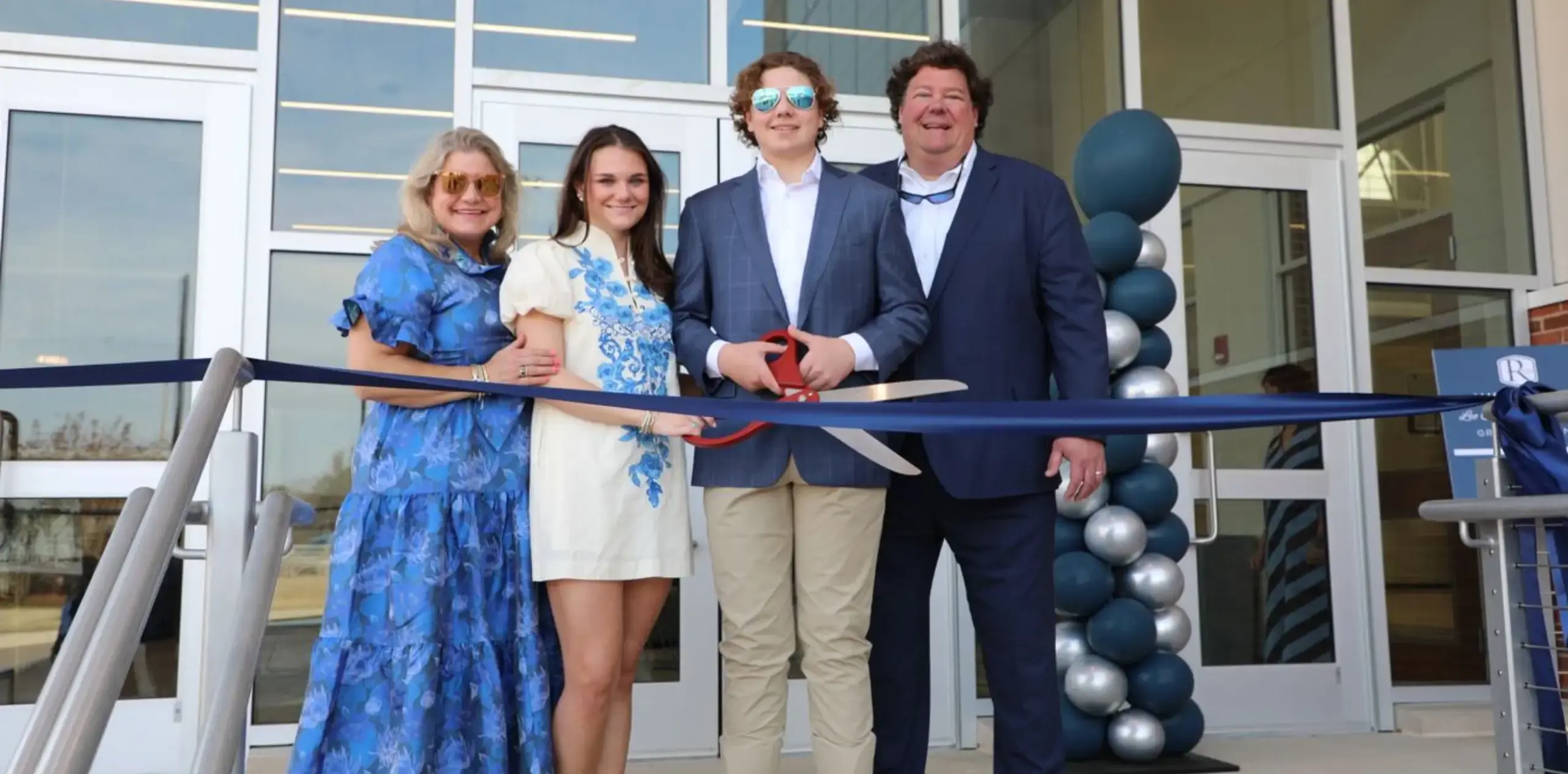 Fmily gathered outside a building during a ribbon-cutting celebration