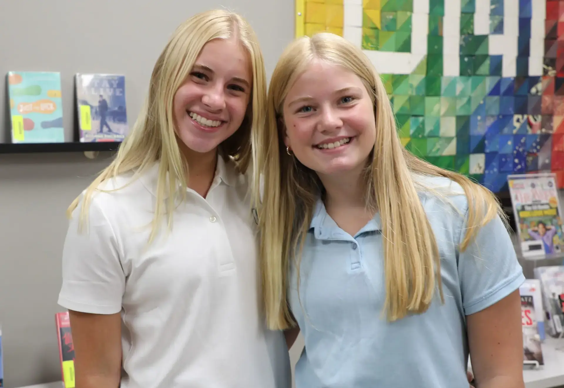 Two smiling students posing together in the school library