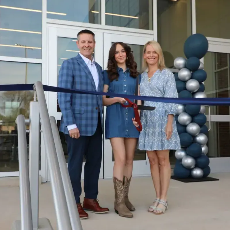Family poses with ceremonial ribbon at Randolph school ribbon-cutting event.