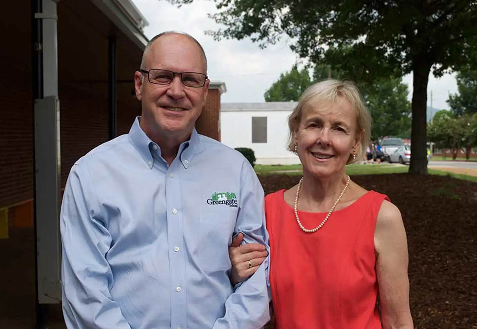 Two smiling adults standing together outdoors 