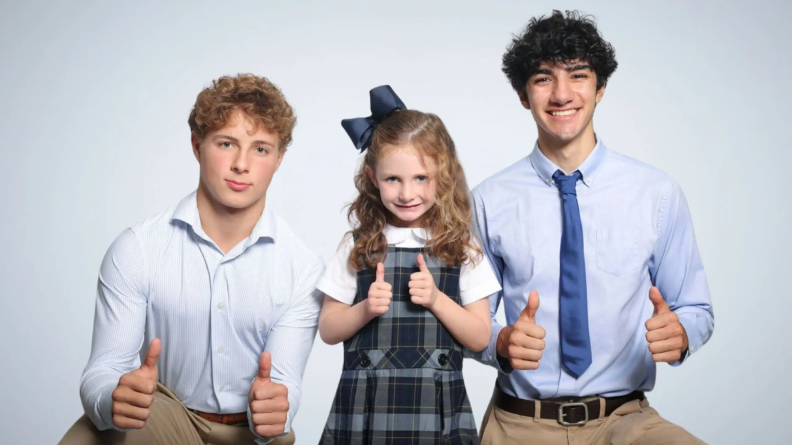 lower, middle and upper school students smiling with their thumbs up